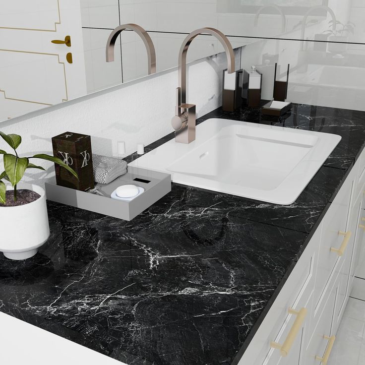 a bathroom sink sitting under a mirror next to a potted plant on top of a counter