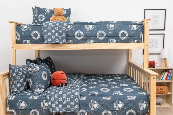 a bunk bed with a basketball on the bottom and blue patterned bedspread over it