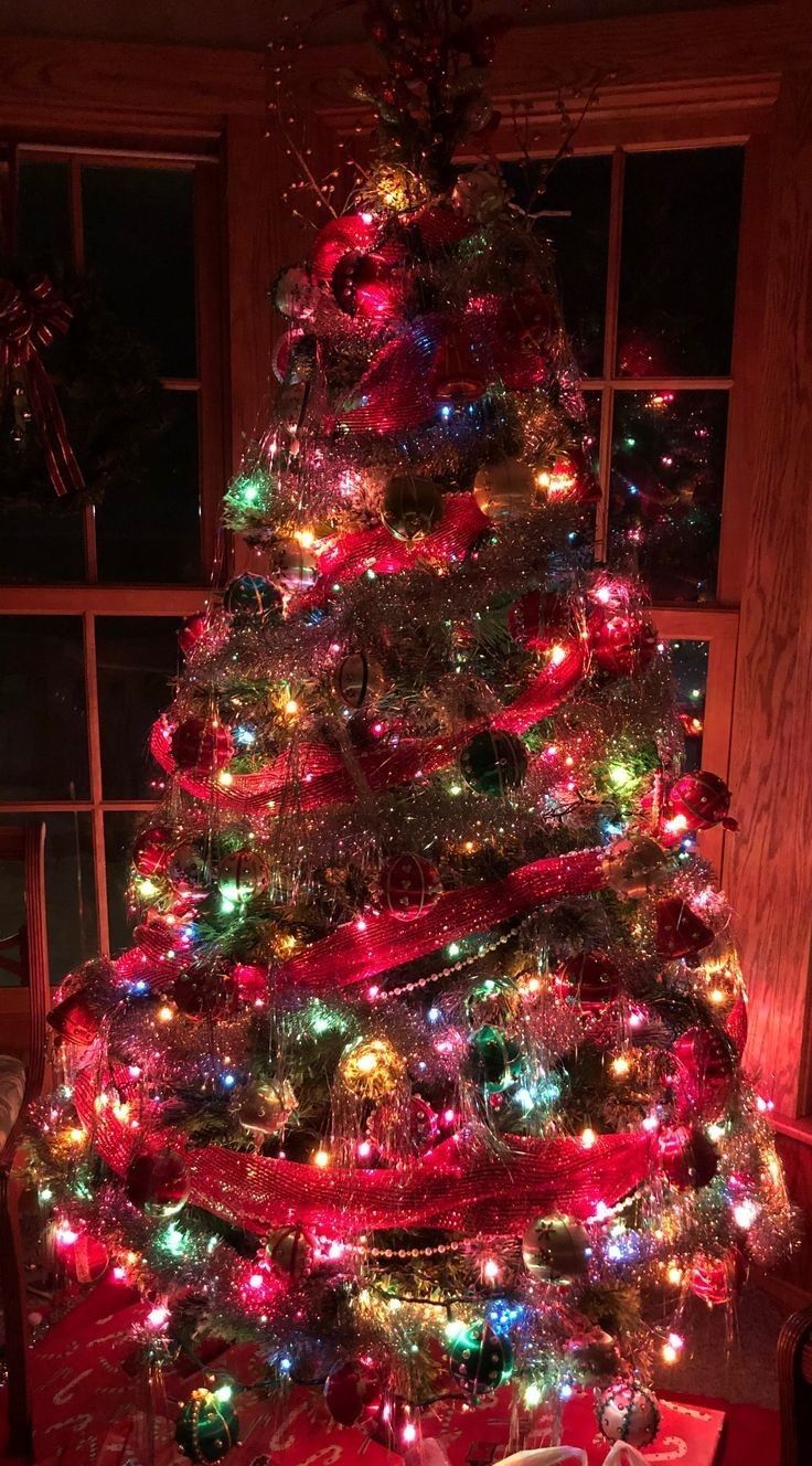 a brightly lit christmas tree in front of a window