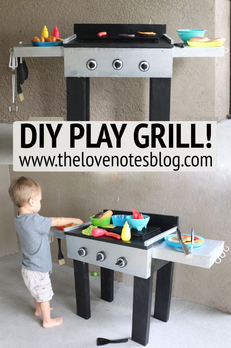 a little boy playing with an outdoor grill on the floor and in front of it