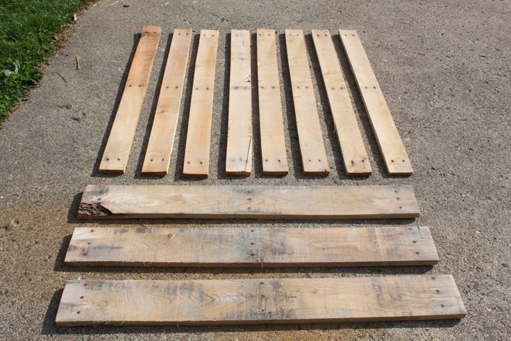 three wooden pallets sitting on top of a cement road next to grass and trees