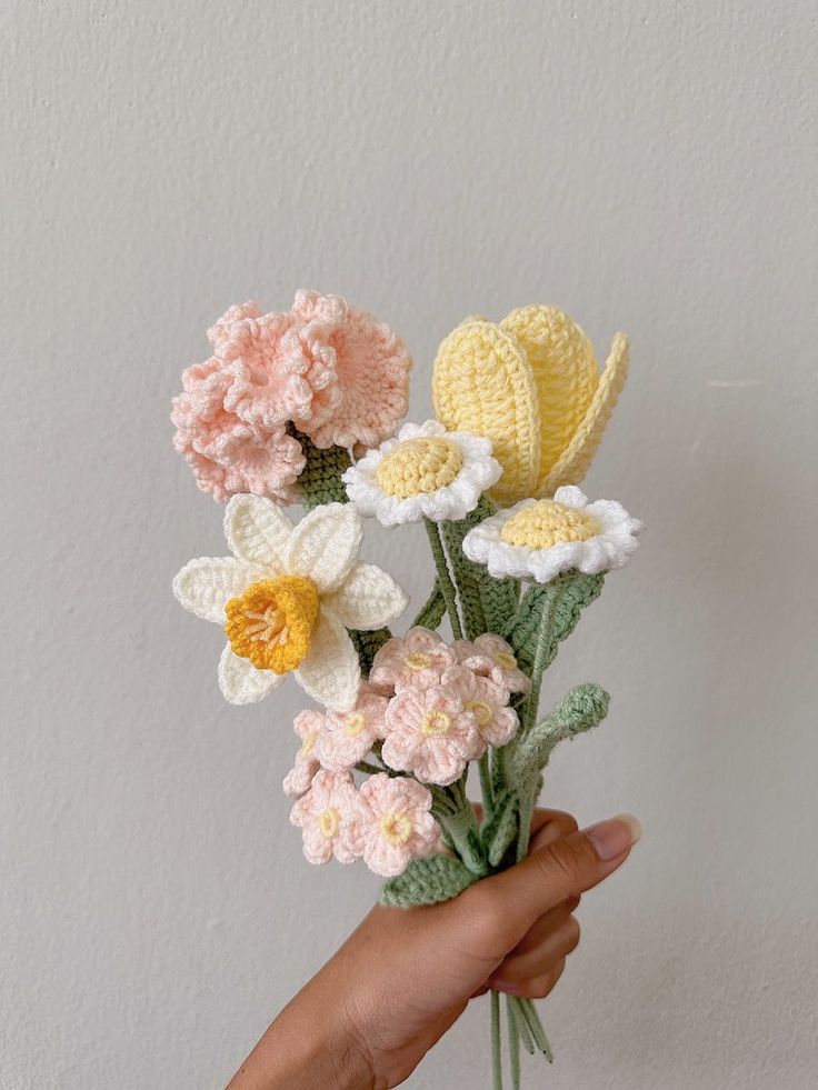 crocheted flowers are being held by someone's hand