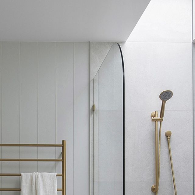 a bathroom with a shower, toilet and sink in it's corner area next to a white tiled wall