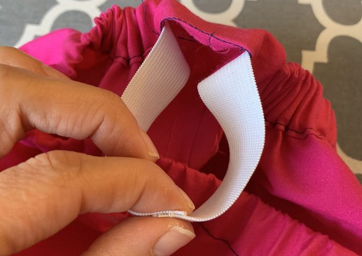 a woman is sewing a red dress with white piping on the front and side