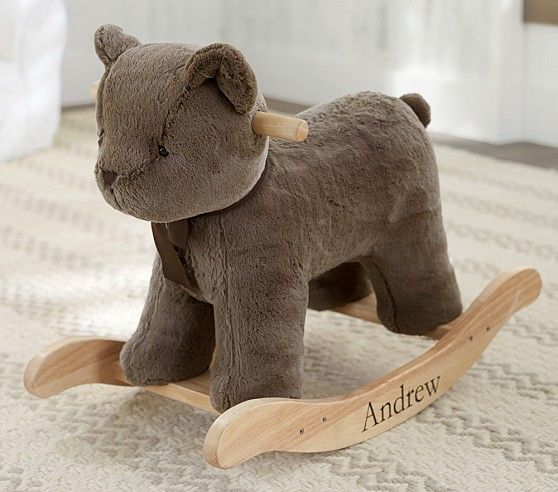 a brown teddy bear sitting on top of a wooden rocking toy