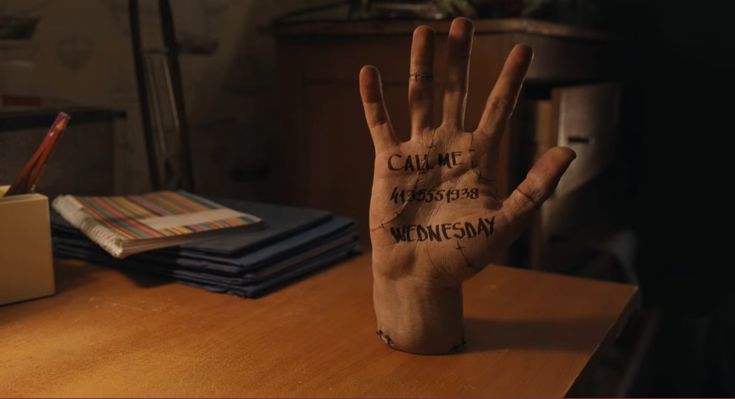 a person's hand with writing on it sitting on a table next to stacks of papers