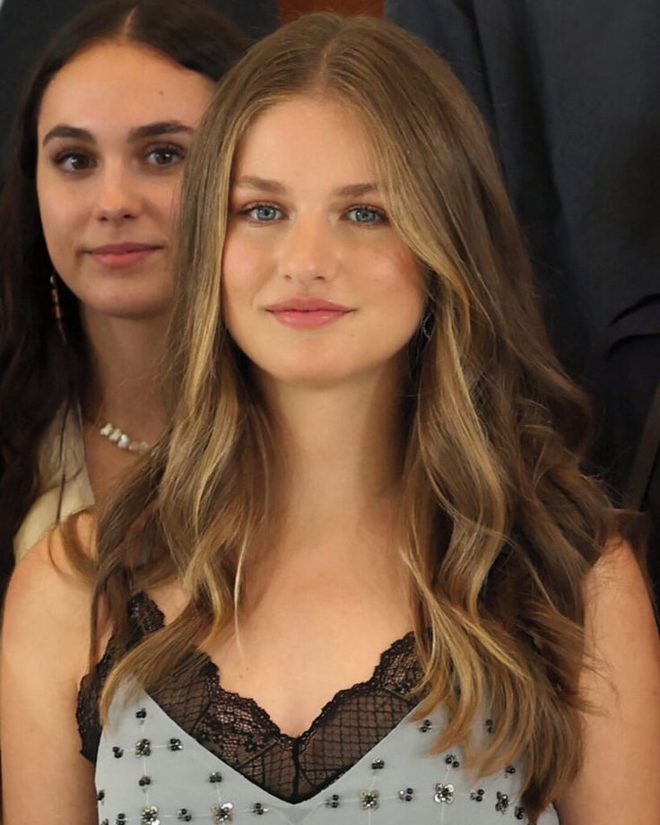 two young women sitting next to each other in front of a man wearing a suit