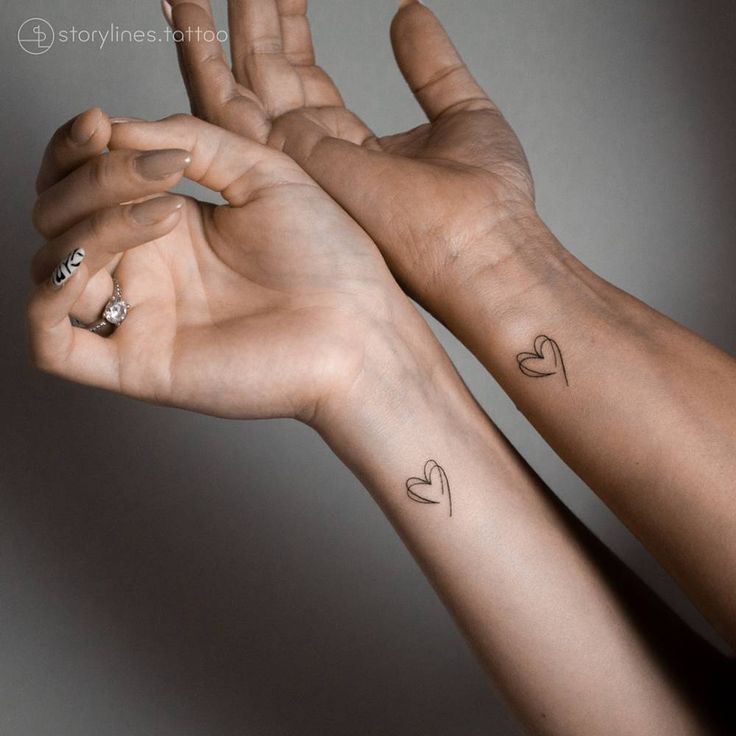 two hands with hearts tattooed on them