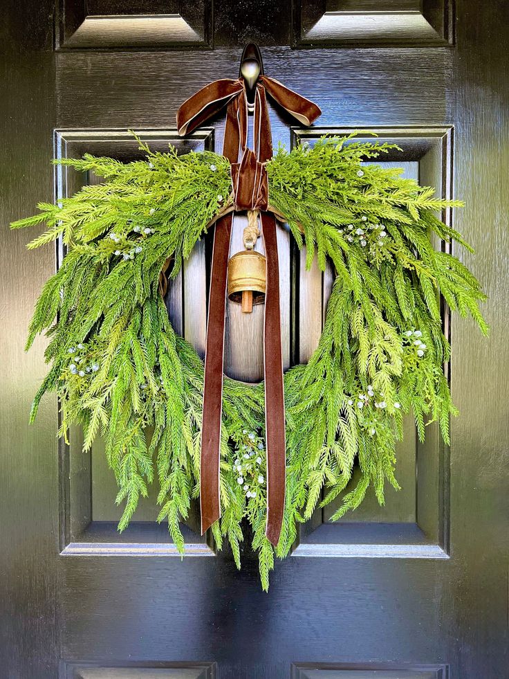 a christmas wreath with bells hanging on a door