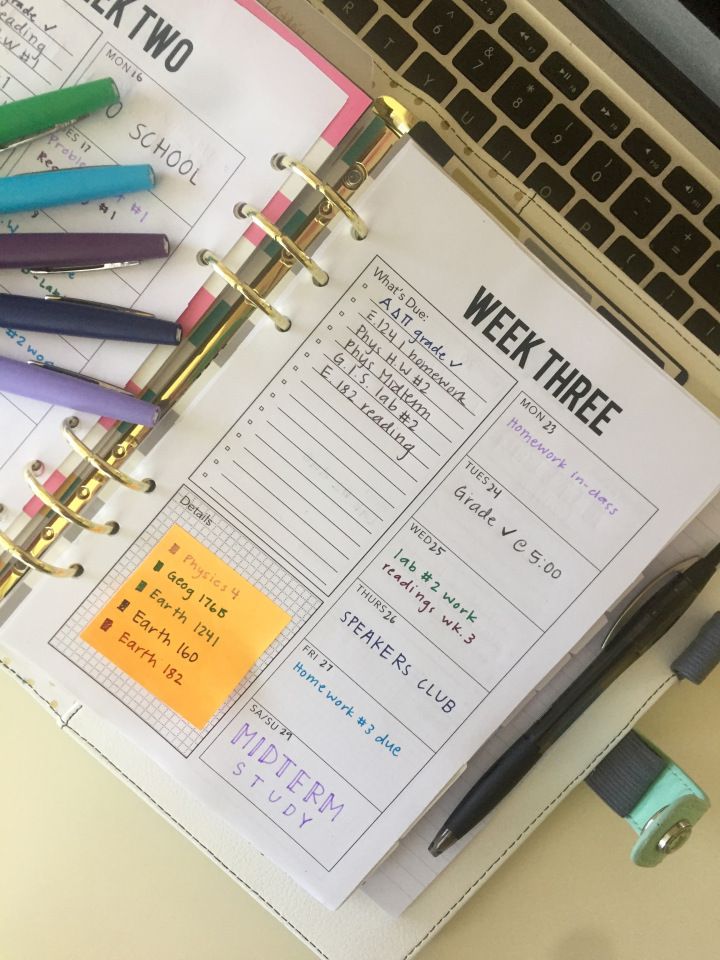 an open planner sitting on top of a desk next to a laptop