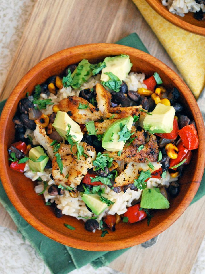 two wooden bowls filled with rice, black beans and avocado on top of a green napkin