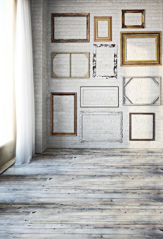 an empty room with frames on the wall and wooden flooring in front of it