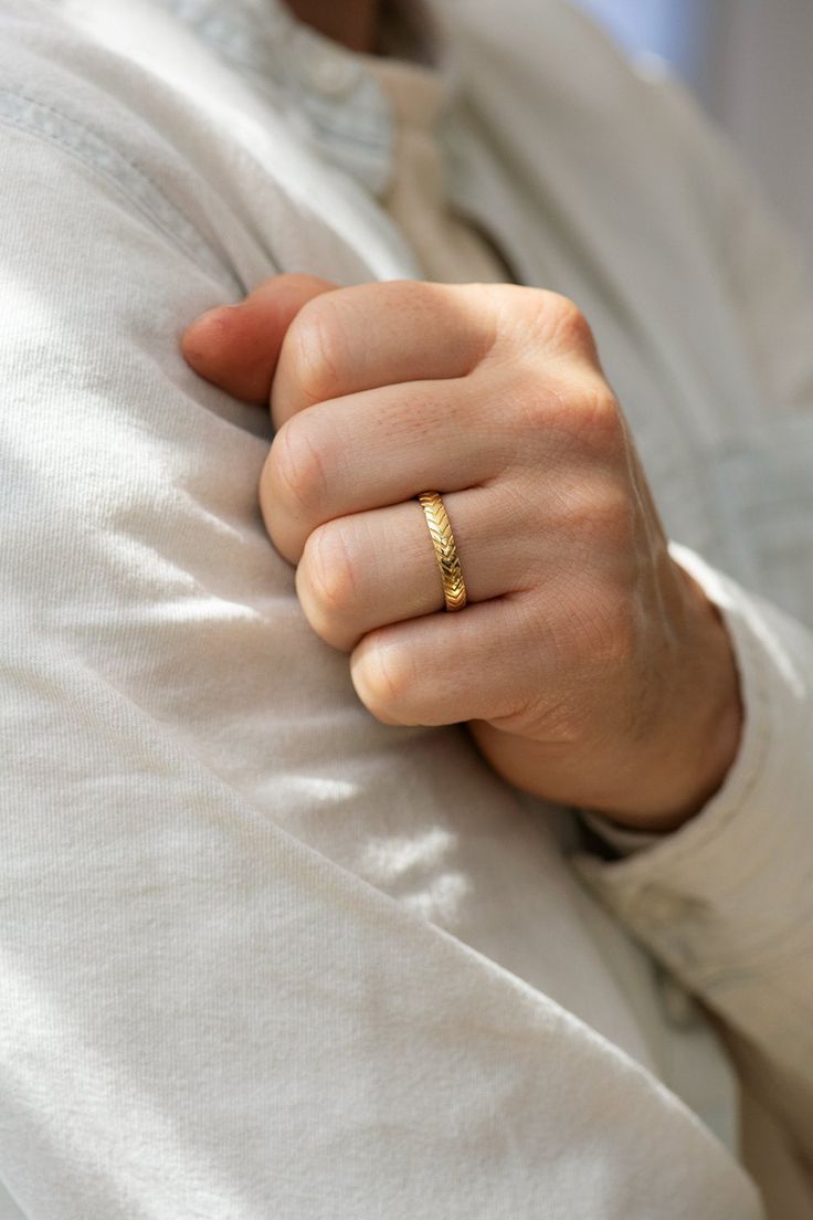 a person wearing a gold ring on their left hand and holding onto the other arm