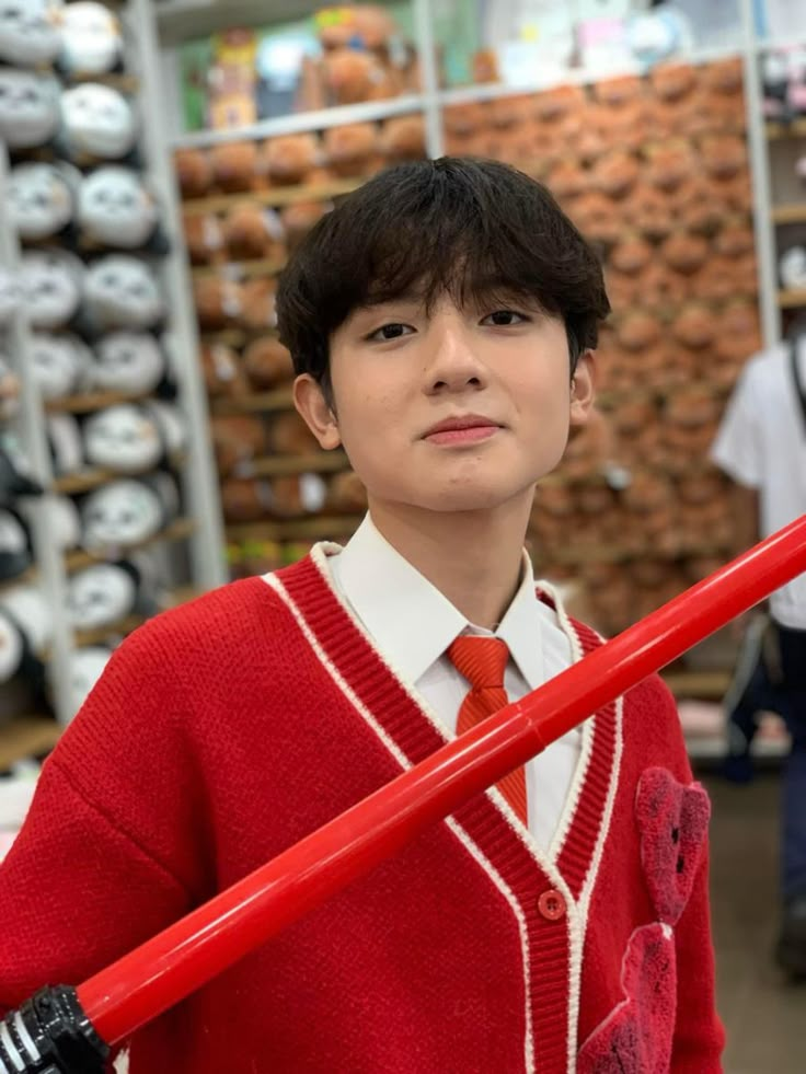 a boy in a red sweater holding a large stick