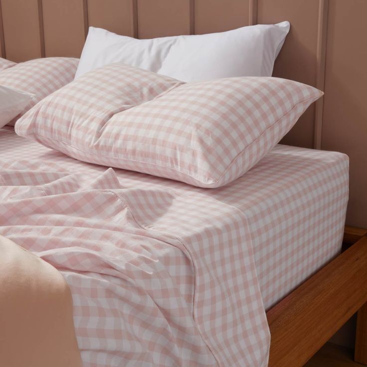 an unmade bed with pink and white checkered sheets