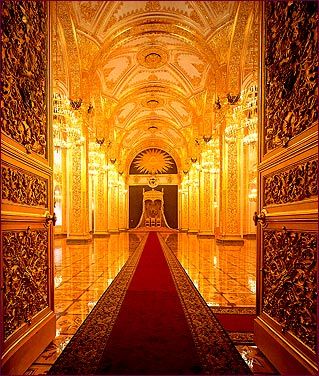 an ornate hallway with gold walls and red carpet