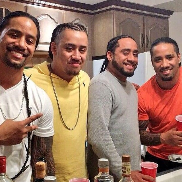 three men standing next to each other in front of a counter with bottles on it