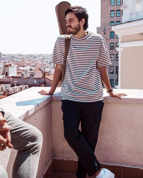 a man standing on top of a roof next to a skateboard in his hand