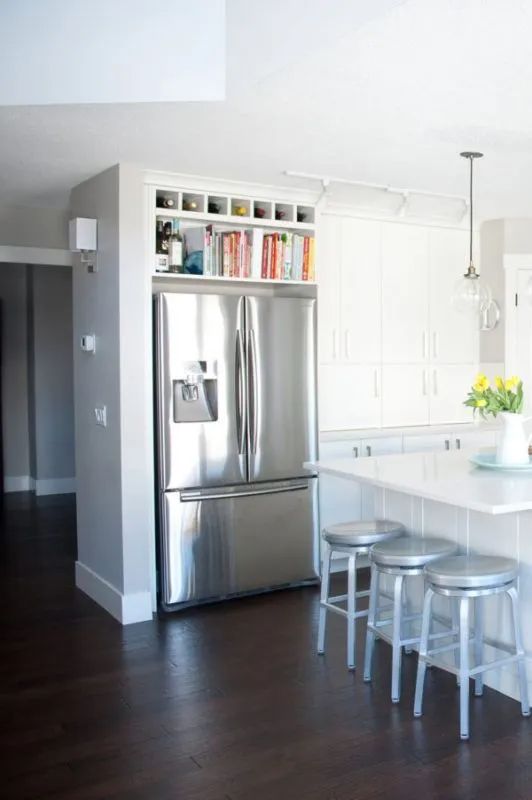 a kitchen with white cabinets and stainless steel refrigerator freezer combo in the center, surrounded by stools