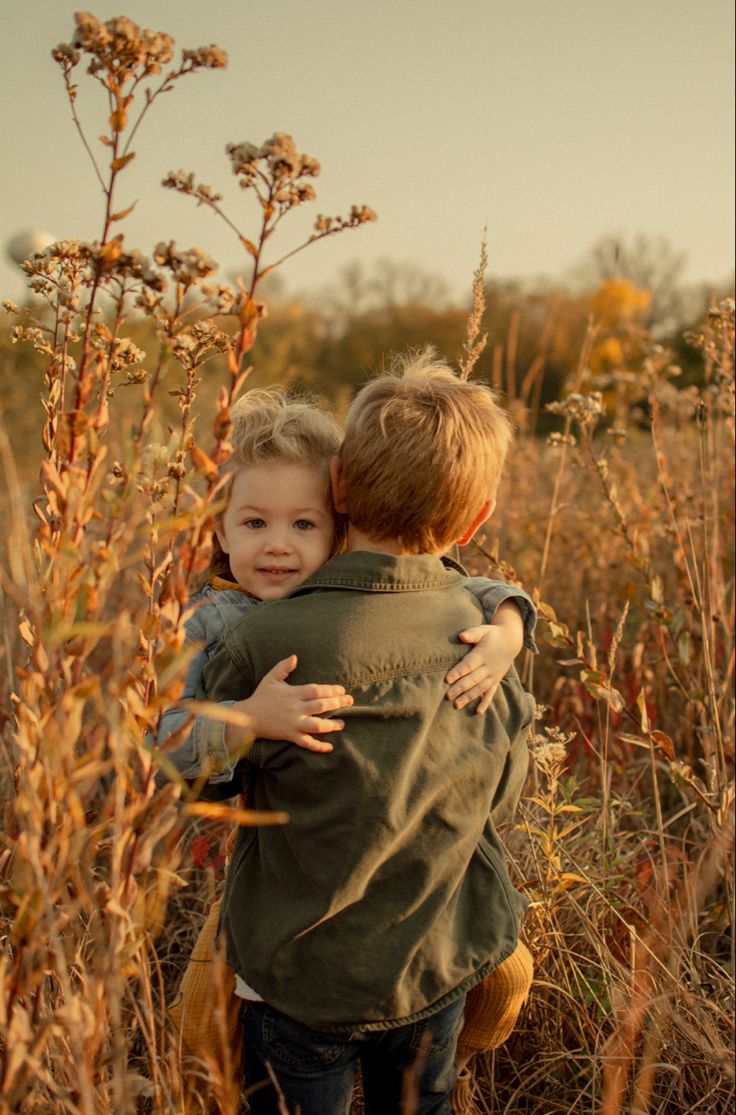 two children hugging each other in the tall grass