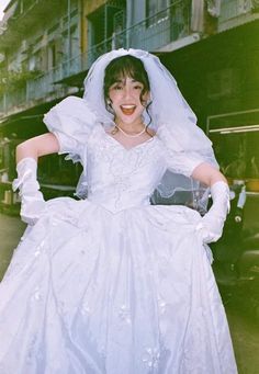 a woman in a white wedding dress and veil posing for a photo with her hands on her hips