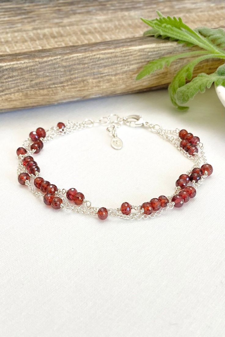 Three strands of microfaceted garnets and sleek rolo chain make an elegant statement. Lobster clasp and extender chain allow for an adjustable fit. Length: 7.5 inches plus 1 inch extender Materials: garnet gemstone, sterling silver Jewelry pouch and gift box included. Elegant Amber Bracelets With Polished Beads, Elegant Amber Beaded Bracelets, Elegant Cranberry Garnet Jewelry, Double Strand Sterling Silver Bracelet For Gift, Sterling Silver Double Strand Bracelet Gift, Elegant Burgundy Jewelry With Faceted Beads, Elegant Burgundy Bracelets As Gifts, Elegant Burgundy Jewelry With Round Beads, Elegant Burgundy Round Beaded Jewelry