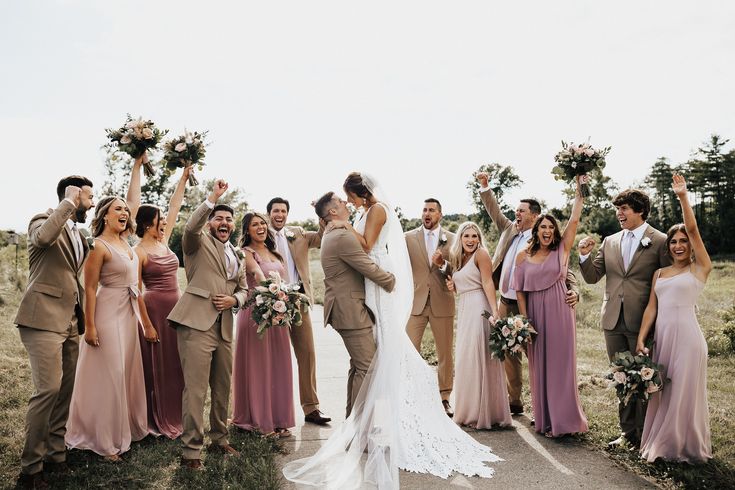 a group of people standing next to each other on top of a dirt road holding flowers