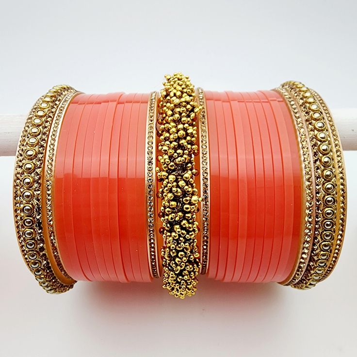 Embrace the warmth and vibrance of your special day with our Orange Bridal Choora, a radiant masterpiece that exudes elegance and charm. Crafted with meticulous care, this choora features a captivating shade of orange that symbolizes joy and enthusiasm. At its heart, the choora boasts golden beaded clusters, a striking focal point that adds a touch of opulence and uniqueness to this bridal accessory. To further elevate its beauty, topaz gold accents grace the choora, lending a shimmering and reg Festive Orange Jewelry For Gift, Festive Orange Jewelry Gift, Traditional Orange Jewelry For Celebration, Traditional Orange Jewelry For Diwali, Orange Round Jewelry For Festivals, Adjustable Orange Jewelry For Festivals, Orange Festive Jewelry For Celebration, Festive Orange Jewelry For Celebration, Orange Festive Celebration Jewelry