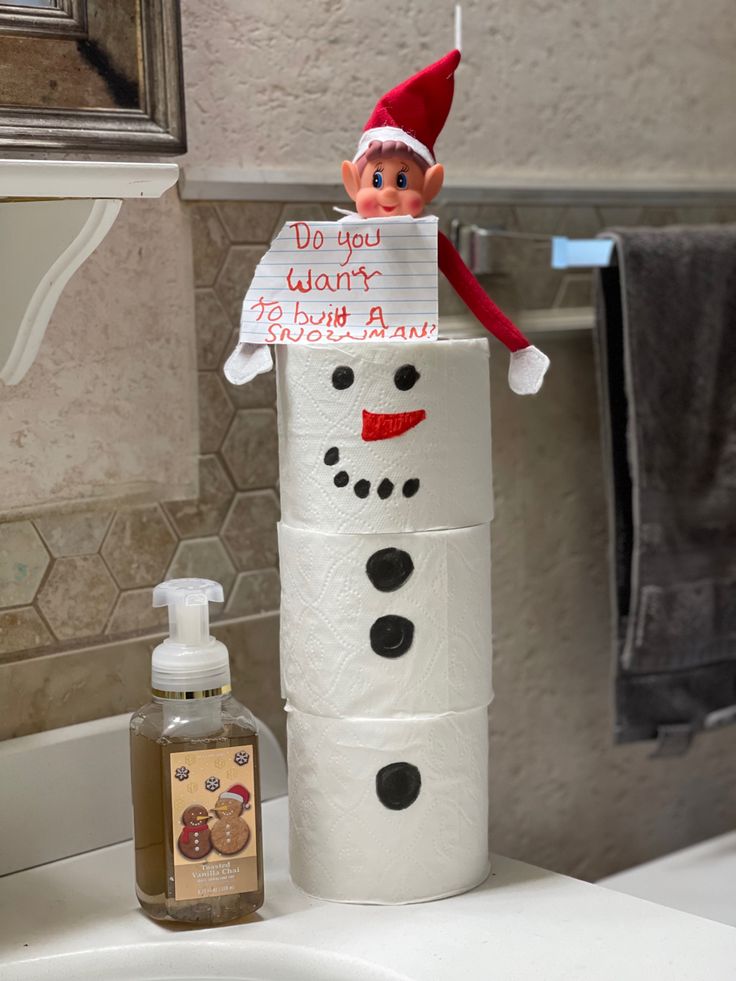 an elf is sitting on top of a toilet paper roll with a sign attached to it