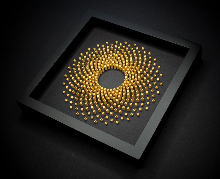 a black frame with yellow beads in the center on a dark surface, as if it were made out of paper