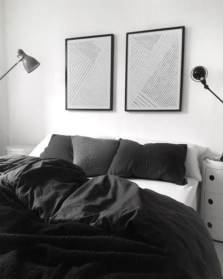 a black and white photo of a bed with two pictures on the wall above it