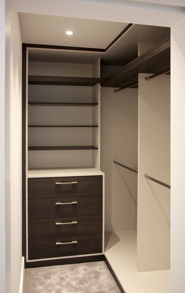 an empty walk in closet with white walls and dark wood drawers on the bottom shelf