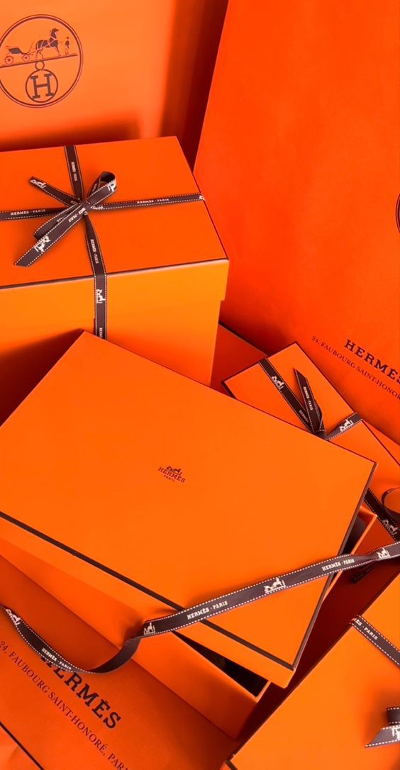 several orange boxes with scissors tied to the top and one on each side, all wrapped in silver ribbon