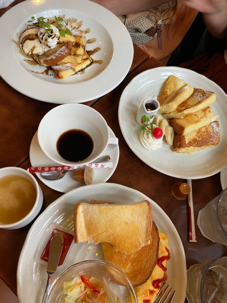 the table is full of breakfast foods and drinks, along with two cups of coffee