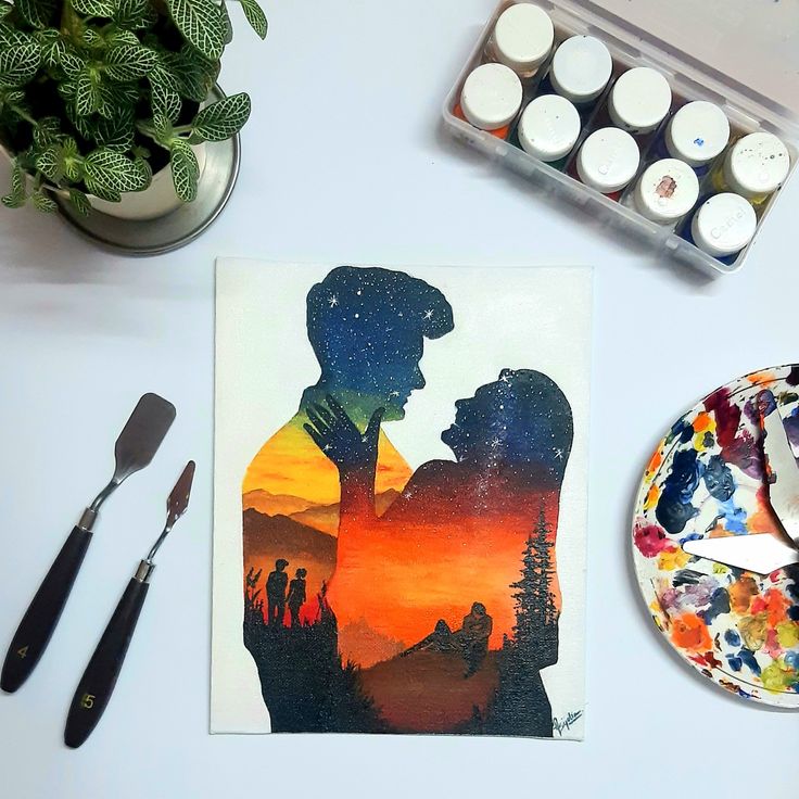 a couple is silhouetted against the sunset with paintbrushes and other art supplies