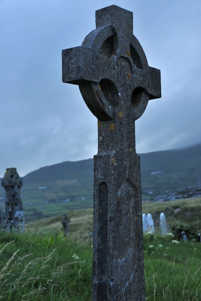 an old stone cross sitting in the middle of a field