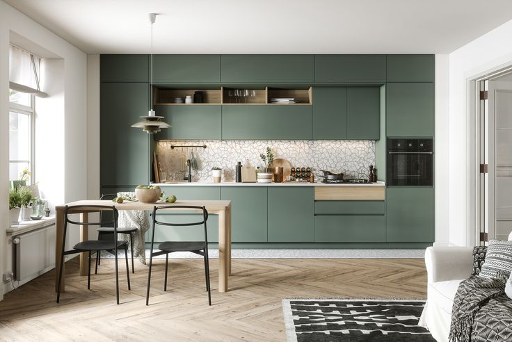 an open kitchen and dining room area with green cabinets, white walls and wood flooring