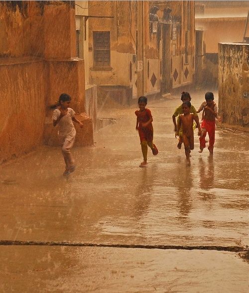 three children are running in the rain with umbrellas