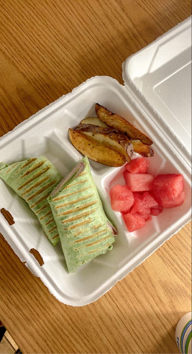 a plastic container filled with food on top of a wooden table