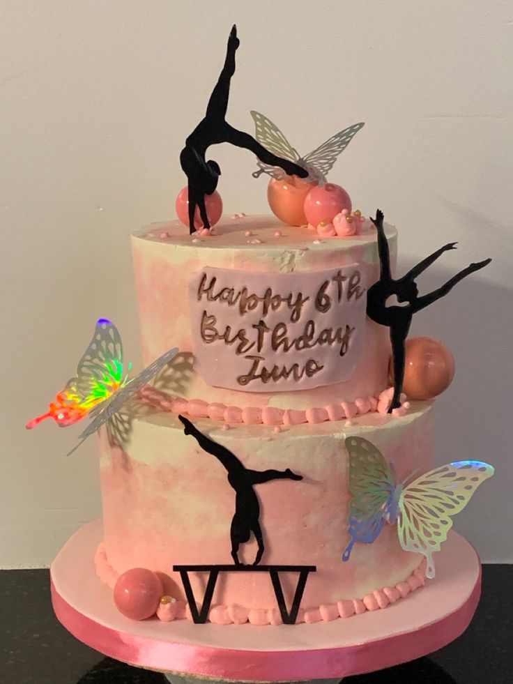 a birthday cake decorated with pink icing and ballet silhouettes on the top tier