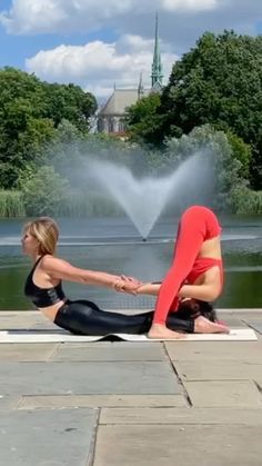 two women doing yoga in front of a fountain