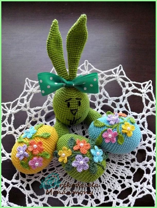 two knitted easter eggs on a doily with a green bow and flower decoration