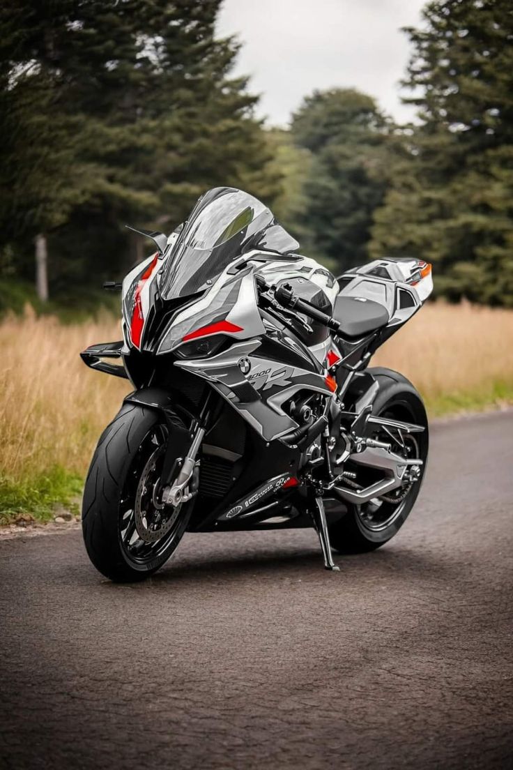 the motorcycle is parked on the side of the road in front of some tall grass