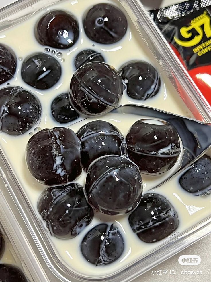 chocolate covered donuts are in a plastic container with milk and candy bar on the side