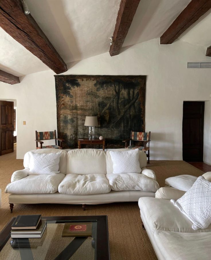 a living room filled with white furniture and a painting on the wall above it's fireplace