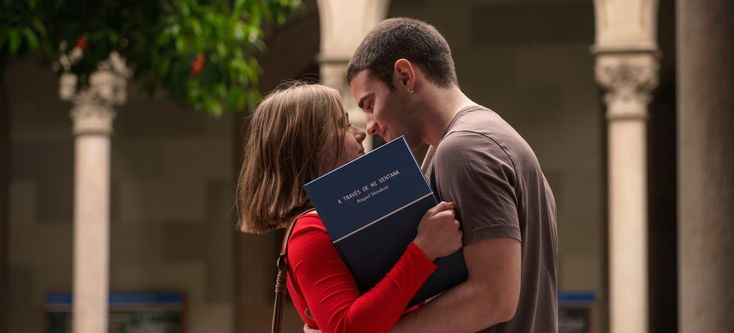 a man and woman embracing each other while holding a book