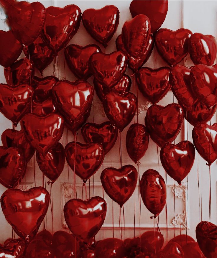 many red heart shaped balloons hanging from strings