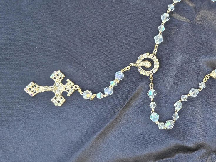 a rosary on a black cloth with an ornate cross hanging from it's center