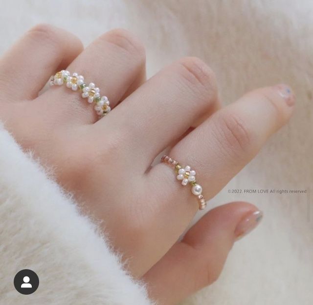 a woman's hand with two rings on it, one is gold and the other is white