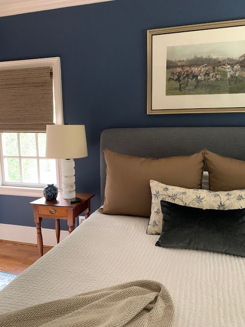 a bed in a bedroom with blue walls and brown pillows on top of it, next to a window